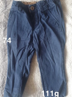 Mörkblå chinos för barn - Snygga mörkblå chinos för barn med klassisk passform och knappstängning i midjan. Byxorna har sidfickor, perfekta för en stilren look.🌸 Fint använt skick. Storlek 74 