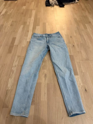 Ljusblå jeans  - Säljer ett par ljusblå jeans från H&M med tapered regular fit. Klassisk femficksmodell, normal midja och raka ben som smalnar av. Tillverkade i mjukt bomullsjeans-tyg, perfekta för en avslappnad och stilren look.
