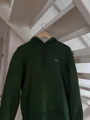 Lacoste Hoodie - Säljer en snygg Lacoste hoodie i storlek S, skick 7/10. Pris kan diskuteras vid snabba affär. Lite solblekt på armen