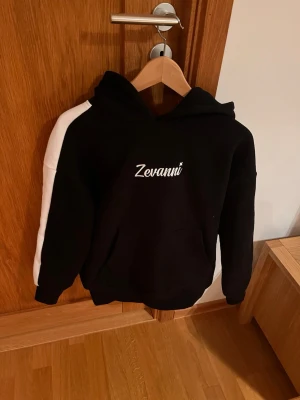 Snygg hoodie från zevanni - Snygg och stilren svart hoodie från ”Zevanni” i skönt material i storlek S. Hoodien har vita detaljer på armen. Hör av dig vid minsta fundering eller lägg ett prisförslag 😇