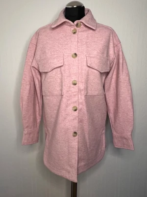 Ljusros overshirt från H&M, XS Oanvänd - Snygg rosa overshirt från H&M i storlek XS. Jackan har klassisk krage, två bröstfickor med lock och stora knappar framtill. Perfekt lager-på-lager-plagg med lång ärm och avslappnad passform.