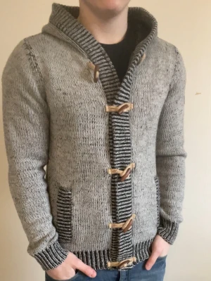 Grå stickad cardigan - Otroligt fet grå stickad cardigan. Perfekt nu till vintern. Modellen är 180cm, 75kg. Priset kan såklart diskuteras!