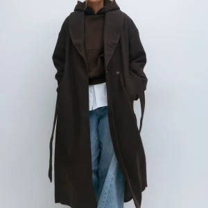 Lång brun kappa - ”Shawl collar long coat” från gina i brunt. Aldrig använd med prislapp på, i xs! Intressekollll, slutsåld på hemsidan just nu. Ordinarie pris 899kr