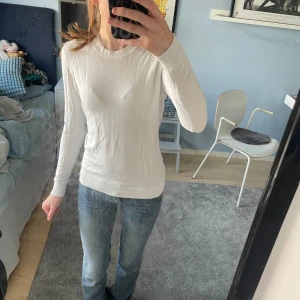 Vit långärmad stickad tröja - Säljer en enkel och stilren vit stickad tröja med rund hals och långa ärmar. Tröjan har en slim passform och är gjord i mjukt material som sitter skönt mot kroppen. Perfekt att matcha med jeans eller kjol för en clean look. Superskön och tunn, men värmande!!