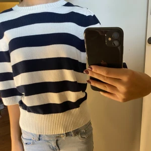 Randig tröja Holly & Whyte S - Superfin stickad tröja från Holly & Whyte i marinblått och vitt med breda ränder. Tröjan har halvlånga ärmar, ribbade muddar och en söt knytning i nacken. Perfekt till jeans för en chill och snygg look.