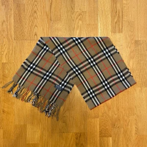 Beige Burberry halsduk i Kashmir - Säljer en beige halsduk från Burberry. Halsduken är gjord i 100% kashmir tyg. Var inte rädd för frågor.
