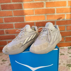 Adidas sneakers i beige/grå, strl 43 - Säljer ett par Adidas sneakers i beige och grå toner med cool futuristisk design. Skorna har snörning, rund tå och detaljer i mocka och syntet. Adiprene-dämpning i sulan för extra komfort. Perfekta för dig som gillar streetwear och snygga detaljer.