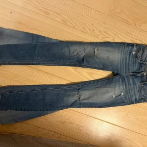 Lågmidjade bootcut jeans med hål från hollister - Säljer dessa lågmidjade jeans från hollister. De står att de är waist 27 men passar även mig som brukar ha waist 25-26. 