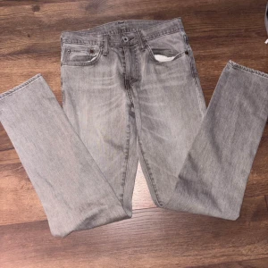 Levi's 511 grå jeans 28/32 - Säljer ett par grå Levi's 511 jeans i storlek 28/32. De har klassisk femficksdesign, smal passform och är tillverkade i mjukt jeanstyg. Snyggt slitna detaljer och ikonisk läderpatch baktill. Perfekta för dig som gillar en stilren och modern look.