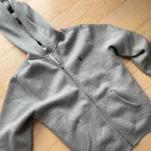 Grå Ralph luren zip hoodie - Säljer en tvär fet Ralph lauren zip hoodie. Storlek är XL för barn så passar runt s och m. Den är använd försiktigt och väl. Vid fler frågor och funderingar är det bara att höra av sig.