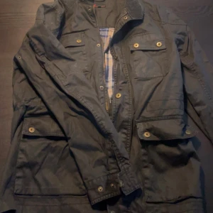 Svart parkajacka från Dressmann - Knappt använd! Super snygg! Mellan M och L. Den är typ svart/grön/blå men det beror på ljus 