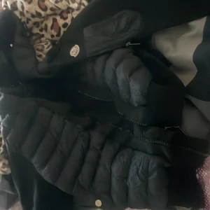 Svart Moncler pufferjacka, storlek S - Säljer en svart pufferjacka från Moncler i storlek S. Jackan har quiltade partier, dragkedja framtill och klassisk Moncler-logga på ärmen. Materialet är en mix av polyester och dun, vilket gör den både lätt och varm. Perfekt för kyliga dagar. Använd endast 1 gång, äkta och söljer för att det var ett onödigt köp för syskonet. Priset kan diskuteras, men håll ra med tanken på att den är äkta.