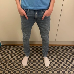 Replay jeans herr - Säljer ett par ljusblå skinny jeans med klassisk femficksdesign och snygga sömdetaljer på bakfickorna. Jeansen har låg midja och är tillverkade i stretchigt denim för en tight passform. Perfekta för dig som gillar en modern och smal siluett.