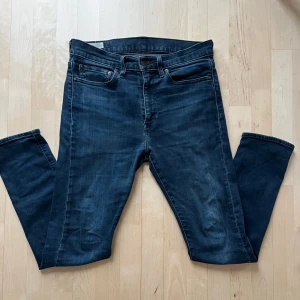 Levi's 512 mörkblå jeans slim fit - Mörkblå Levi's 512 jeans med slim fit och klassisk femficksdesign. Jeansen har en snygg tvätt, normal midja och raka ben. Tillverkade i stretchig denim för extra komfort. Perfekta för dig som gillar en modern och stilren look.