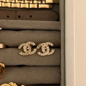  örhängen med strass i guld - Snygga  örhängen, täckta med glittrande strass. De är i guldig ton och har en stilren, ikonisk design som verkligen sticker ut. Perfekta för dig som vill ha något lyxigt och trendigt i smyckesamlingen.