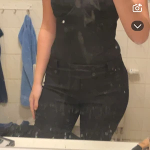 Svarta kostymbyxor med knappar - Snygga svarta kostymbyxor med hög midja och raka ben. Byxorna har dekorativa knappar framtill och en klassisk, stilren look. Perfekta för dig som gillar en clean och dressad stil. Materialet känns mjukt och följsamt.