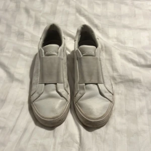 Vita slip-on sneakers Calvin Klein pris kan diskuteras - Snygga vita slip-on sneakers från Calvin Klein med präglad CK-logga på sidorna och sulan. Skorna har bred resår över vristen för enkel påtagning och en stilren, minimalistisk look. Tillverkade i syntetmaterial med platt sula och rund tå.