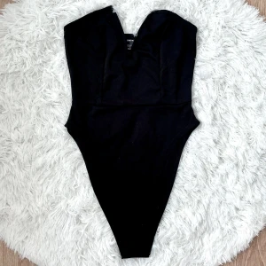 Svart bodysuit från SHEIN med v-ringning - Snygg svart baddräkt från SHEIN med markerad v-ringning och enkel, stilren design. Storlek S (34), byst 83-87cm, midjan 64-68cm.