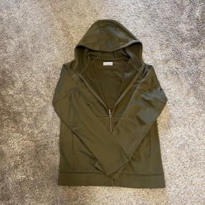 Olivgrön hoodie från Columbia - Säljer en olivgrön hoodie från Columbia med dragkedja och huva. Tröjan är i mjukt fleece material och har långa ärmar samt två fickor framtill. Perfekt för lager-på-lager under kyliga dagar. Enkel och stilren design utan mönster. Det är en XL ungdom, så den har passformen som en S vuxen.