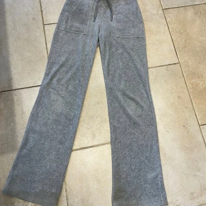 Grå mjukisbyxor Juicy Couture XS - Säljer ett par juicy Couture byxor i storlek XS. byxorna är uppsydda i benen om är 77 cm från grenen! knapparna har tappat lite färg och de är fläckar längst ner på benen! 
