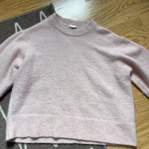 Ljusrosa stickad tröja från Gina Tricot - Supermjuk ljusrosa stickad tröja från Gina Tricot med rund hals och ribbade muddar. Tröjan har en relaxed passform och är tillverkad i en blandning av akryl, polyester, ull och alpacka. Perfekt för kyliga dagar när du vill vara både bekväm och snygg.