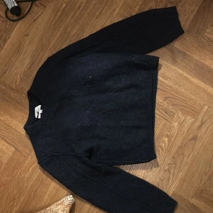 Mörkblå stickad tröja från &otherstories - Mysig mörkblå stickad tröja från &otherstories med rund halsringning och ribbade muddar. Perfekt för kyliga dagar och enkel att matcha med jeans eller kjol. Klassisk och stilren design som funkar året runt.