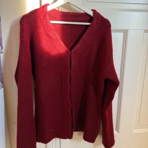Vinröd kofta med v-ringning - Mysig vinröd kofta med v-ringad hals och långa ärmar. Koftan är stickad och har knappar framtill. Perfekt för lager-på-lager och passar till många olika stilar. Storleken är oversized M💓
