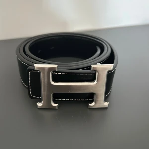 Svart bälte med H-spänne - Snyggt svart bälte  H-spänne i. Perfekt accessoar för att lyfta din outfit med en lyxig touch och klassisk design.