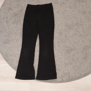 Svarta bootcut byxor från Lindex - Svarta byxor från Lindex i stretchigt och mjukt material. Modellen har bootcut-ben och resår i midjan för extra komfort. Perfekta för dig som gillar en enkel och clean look med lite utsvängda ben.