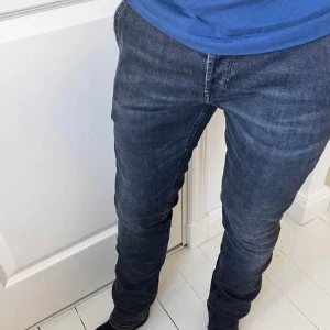 Gråa skinny jeans från Dondup - Säljer ett par mörkblå skinny fit jeans från Dondup i storlek 34. Jeansen har smal passform och är tillverkade i stretchigt denim för extra komfort. Perfekt för dig som gillar en tajt och modern look. Hör av er vid eventuella frågor!
