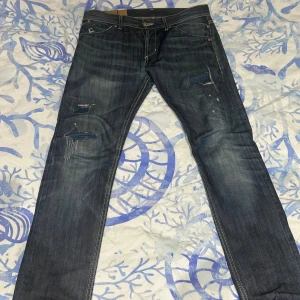 Dondup jeans  - Mörkblå Dondup jeans med snygga slitningar och lagade detaljer på benen. Klassisk femficksmodell med kontrastsömmar och coola bakfickor med orange brodyr. Jeansen har rak passform och är tillverkade i robust denim.