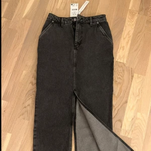 Svart lång jeanskjol med slits - Svart långkjol i jeans från NA-KD med slits framtill. Svårt att visa på bild men den räcker ner till marken på mig som är 162cm.