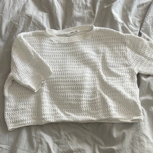 Vit virkad croppad topp  - Superfin vit croppad topp från mango med virkad känsla och korta ärmar. Toppen har ett luftigt, stickat mönster och ribbad kant vid halsen. Perfekt för varma dagar när du vill ha en chill och trendig look.