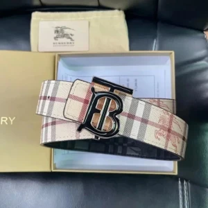 Burberry rutigt skärp med B-spänne - Snyggt Burberry-bälte i klassiskt beige, svart och rött rutmönster med ikoniskt B-spänne i metall. Bältet är gjort i skinn och har en bred design som sticker ut. Perfekt för att lyfta vilken outfit som helst med en lyxig touch.