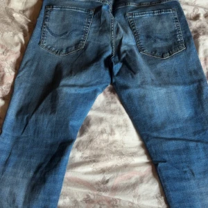 Blå jeans från Jack & Jones - Säljer ett par klassiska blå jeans från Jack & Jones med snygg tvätt och raka ben. Jeansen har fem fickor, normal passform och är tillverkade i bomull. Perfekta för dig som gillar en enkel och stilren look.