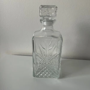 Glaskaraff - Glaskaraff med slipat mönster och kvadratisk kork visas.