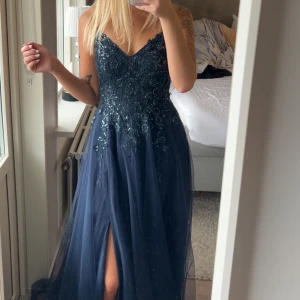 Marinblå balklänning med paljetter - Säljer en marinblå balklänning i superfint skick förutom några småhål längst ner som inte syns vid användning. Strl 34/36. Fler bilder kan fås vid intresse💕💕prislappen som syns på första bilden är inte kvar på klänningen. 