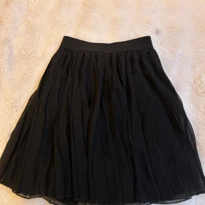 Svart kjol från NA-KD - Supersnygg svart kjol från NA-KD i storlek XS. Kjolen har ett elastiskt midjeband och är gjord i ett lätt, flowy material som ger en riktigt fin siluett. 