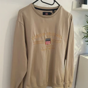 Beige tröja från Vinson Original - Säljer en beige sweatshirt från Vinson Original i storlek S, med broderad logga och text på bröstet. Tröjan har rund hals, ribbade muddar och lång ärm. Perfekt för chill dagar och enkel att matcha med jeans eller joggers. Tröjan är i väldigt fint skick och är sparsamt använd. Vid frågor så är det bara att höra av sig!