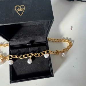 Pärlhalsband Guld - Chunky guldfärgat halsband med stora länkar och hängande vita droppformade pärlor. Snygg statementkedja som ger en lyxig vibe och passar perfekt till lager-på-lager-stil.