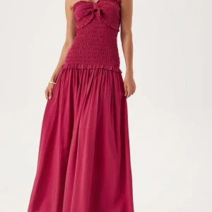 Vinröd långklänning - Supersöt vinröd/mörk rosa långklänning från Andrea Norrman (bubbelroom) med smockad överdel, volangdetaljer och knytband framtill. 