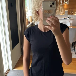 Svart basic t-shirt i bomull - En svart, enkel och stilren t-shirt med rund hals och korta ärmar. Modellen är figurnära och passar perfekt till jeans eller shorts. Materialet är mjuk bomull som känns skönt mot huden. Står på tröjan att den är storlek 158/164 men passar mig som har XS!
