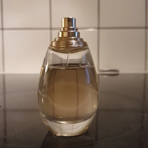 J'adore Eau de Parfum från Dior - Lyxig J'adore Eau de Parfum från Dior. Obs! Har tappat bort korken till flaskan,och kartongen kastad.                      Doften lanserades 1999 och har toppnoter av bland annat magnolia, melon och persika, hjärtnoter som jasmin, ros och liljekonvalj, samt basnoter av mysk, vanilj och cederträ.