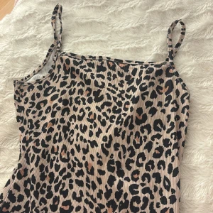 Leopardmönstrad body BikBok XS - Supersnygg leopardmönstrad body från BikBok i storlek XS. Klänningen har smala axelband och är figurnära med ribbad struktur. Färgerna går i beige, svart och bruna toner. Perfekt för dig som vill sticka ut med ett djurmönster!