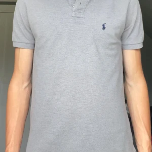 Grå Ralph Lauren piké - Hej, en grå piké med mörkblått märke på bröstet. Använd fåtal gånger därav inga defekter alls.  📐Mått och storlek: Det är en S och normalstor i storleken. Jag är 180cm och 63kg Bröstvidd: 36cm Ärmlängd: 18cm Midjemått: 47cm Plagglängd: 61cm Hör av er om ni har frågor ⭐️