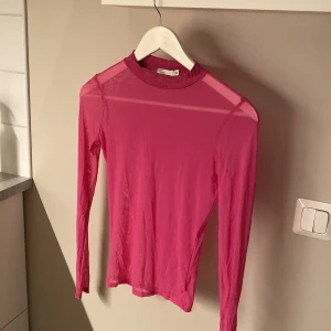 Rosa meshtröja från NLY Trend XS - Säljer en tunn och transparent rosa meshtröja från NLY Trend i storlek XS. Tröjan har lång ärm och en tight passform, perfekt att styla lager på lager eller med ett snyggt linne under. Enkel och stilren design med rund hals.