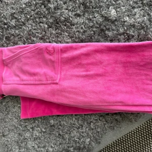 Juicy Couture xxs - Juicy Couture velourbyxa cerise i xxs, mer som xs. Jättefint skick. Dock har en liten silverring vid snöret försvunnit. Se bild. 500:-