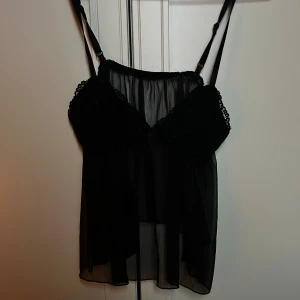 Svart spetsig linnetopp från SHEIN - Säljer en svart linnetopp från SHEIN i storlek XS. Toppen har tunna justerbara axelband, spetsdetaljer över bysten och är gjord i transparent polyester. 