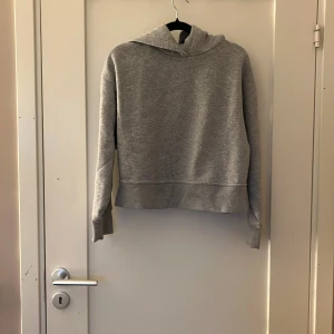 Grå hoodie från Zara med slits - Mysig grå hoodie från Zara i mjuk bomullsblandning. Tröjan har huva, långa ärmar och coola slitsar vid ärmsluten. Perfekt för chill dagar och enkel att matcha med jeans eller leggings.
