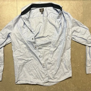 Ljusblå skjorta  - Detta är en ljusblå H&M skjorta i storlek M. Den är näst intill oanvänd och passar perfekt för lite mer uppkläda tillfällen 